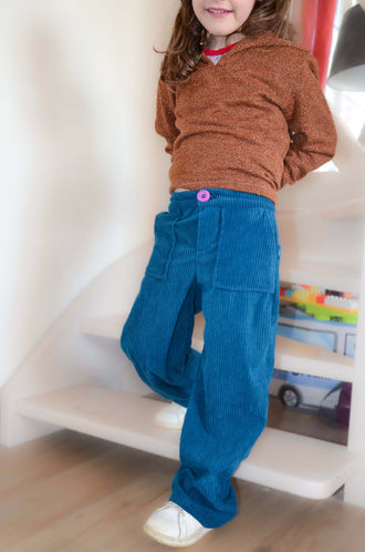 Enfant portant le Pantalon BAGGY ALVIDA avec coupe large et poche cuisse, patron de couture pdf à télécharger, en tissu bleu.
