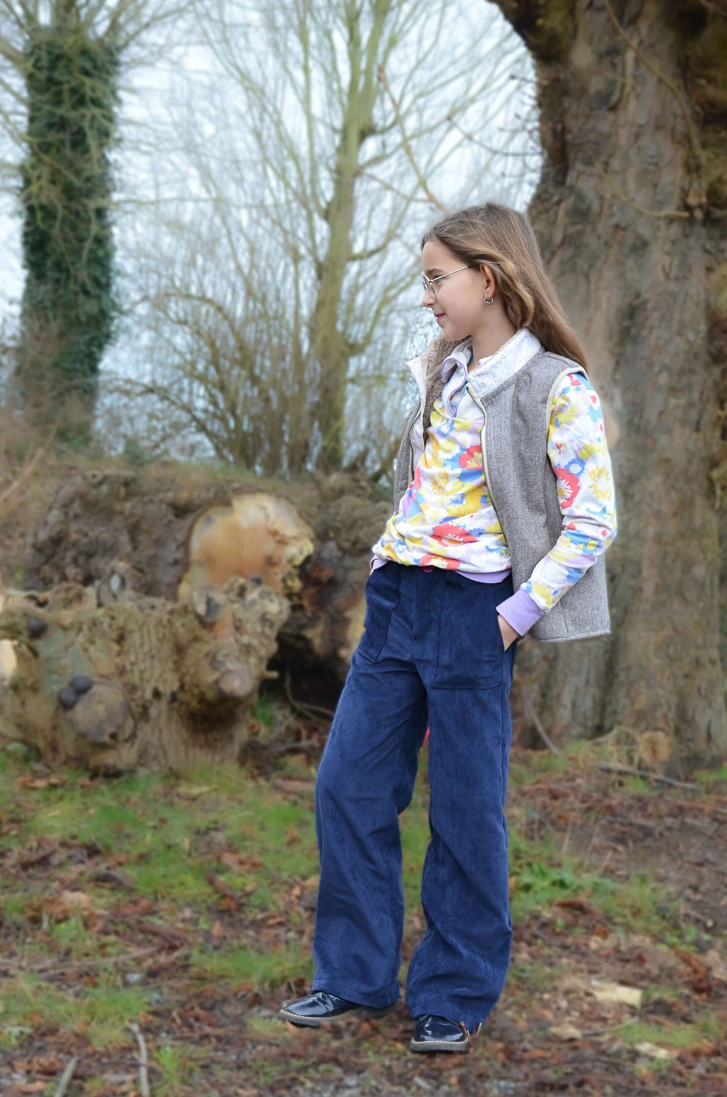 Jeune fille portant un Pantalon BAGGY ALVIDA avec patron de couture pdf à télécharger, en extérieur devant un arbre.