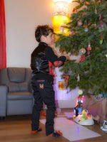 Enfant portant un Pantalon Enfant EBENE lors de fêtes près d'un sapin de Noël, patron de couture PDF à télécharger disponible.