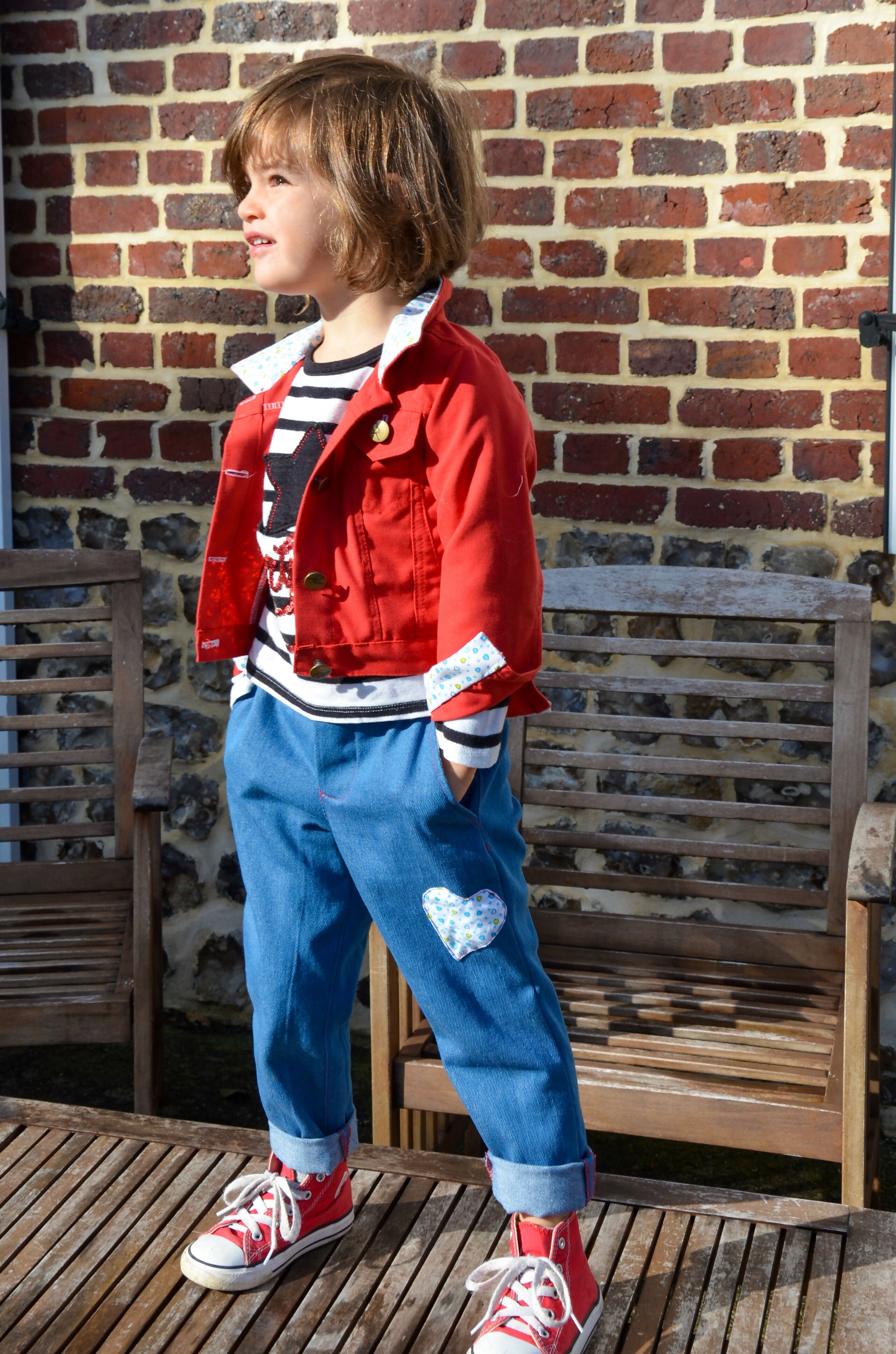 Enfant portant un Pantalon Enfant EBENE et une veste rouge, idéal pour un look décontracté, avec patron de couture pdf à télécharger.