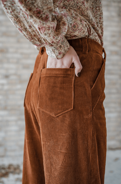Pantalon OPAZ à taille haute et jambes larges, avec poches italiennes et tissu côtelé en couleur brun.