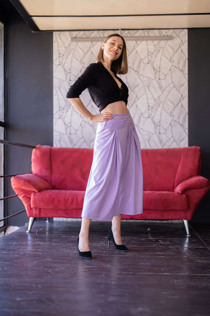 Femme portant un pantalon vintage lavande sur fond de canapés rouges, présentation de Pantalon - XXS-XL - VINTAGE CADILAC.