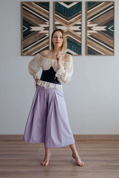 Femme portant un pantalon - XXS-XL - VINTAGE CADILAC avec un haut blanc et noir, sur un sol en bois.