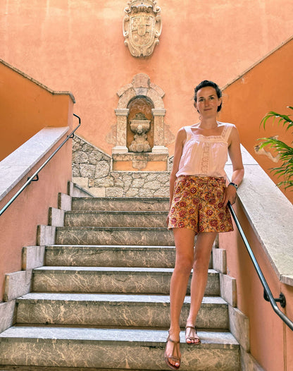 Femme portant un short Pantalon ou short Orsi, patron de couture PDF à télécharger, debout sur des escaliers pittoresques.