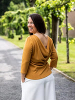 Femme portant la Blouse Bénitier PINA COLADA en jersey ocre, vue de dos, allée arborée