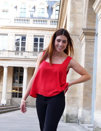 Femme portant le Patron PDF Débardeur Manille du 32 au 48 en rouge vif, vue de face dans une cour parisienne