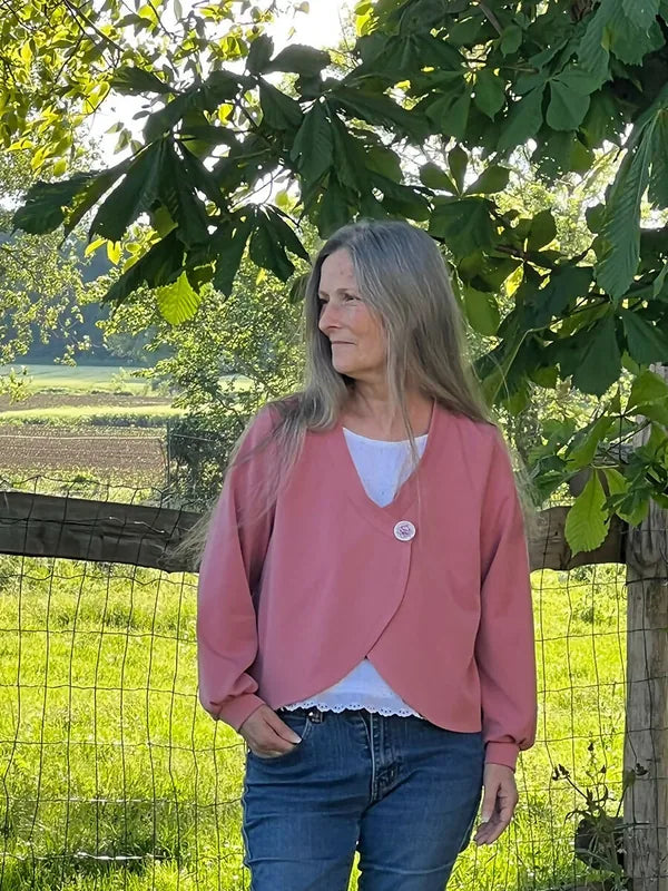 Femme portant le Patron PDF Gilet Tourmaline, cardigan rose ouvert sur chemise blanche à dentelle, jean bleu