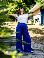 Femme portant le Patron PDF PECAN - Pantalon à Plis femme/enfant en bleu, debout dans un jardin