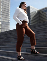 Femme portant le Patron PDF Pantalon Jasmin en velours caramel, vue de profil en milieu urbain