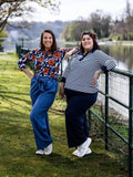 Deux femmes portant le Patron PDF Polo multi-manches Kiwi, debout au bord d'un lac, souriant à la caméra