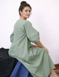 Femme portant le Patron PDF Robe longue IRIS, manches courtes en lin, assise de profil, vue n°6