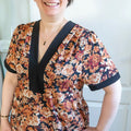 Femme portant le Patron PDF Robe courte Pomme Golden, manches courtes, col en V avec bande noire, imprimé floral orangé