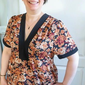 Femme portant le Patron PDF Robe courte Pomme Golden, manches courtes, col en V avec bande noire, imprimé floral orangé