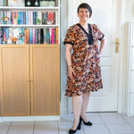 Femme portant le Patron PDF Robe courte Pomme Golden, manches courtes à fleurs, debout dans un intérieur blanc