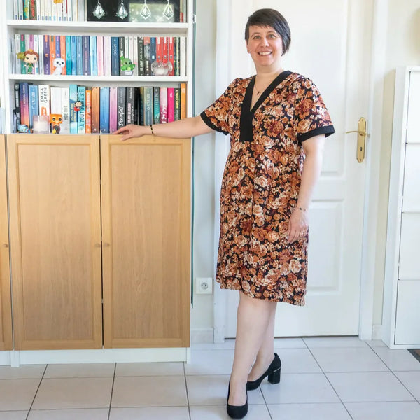 Femme portant le Patron PDF Robe Pomme Golden, robe courte fleurie à manches courtes et col V, imprimé floral sur fond noir
