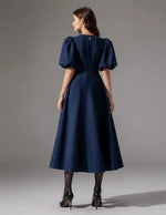 Femme portant le Patron PDF Robe longue Olga, vue de dos en denim bleu marine, manches bouffantes, jupe ample et fluide