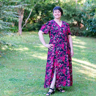 Femme portant la robe "Patron PDF Robe longue Pomme Gala du 34 au 56" avec motif floral, idéale pour couture, dans un jardin.