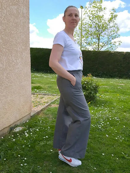Femme portant le Patron PDF Pantalon A du 32 au 60, vue de côté en sergé gris, debout dans un jardin