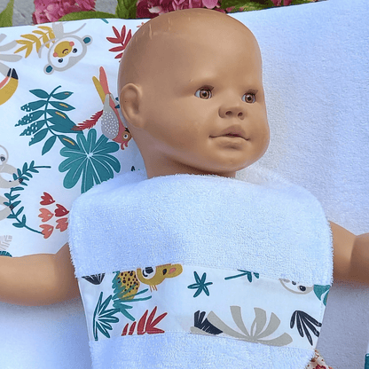 Patron pdf du bavoir bébé présenté sur une poupée avec une face en éponge et des motifs colorés.