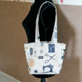 Petit Tote Bag avec fond en coton, motifs couture et couturière, porté sur buste mannequin noir, vue de face
