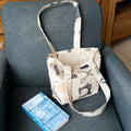 Petit Tote Bag avec fond en coton, posé sur fauteuil gris avec motifs couture, vue du patron