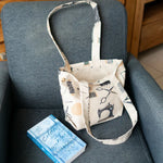 Petit Tote Bag avec fond en coton, posé sur fauteuil gris avec motifs couture, vue du patron