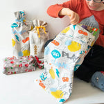 Enfant découvrant des cadeaux dans une pochette cadeaux zéro déchet, 6 formats – Oooh!, patron de couture pdf à télécharger.