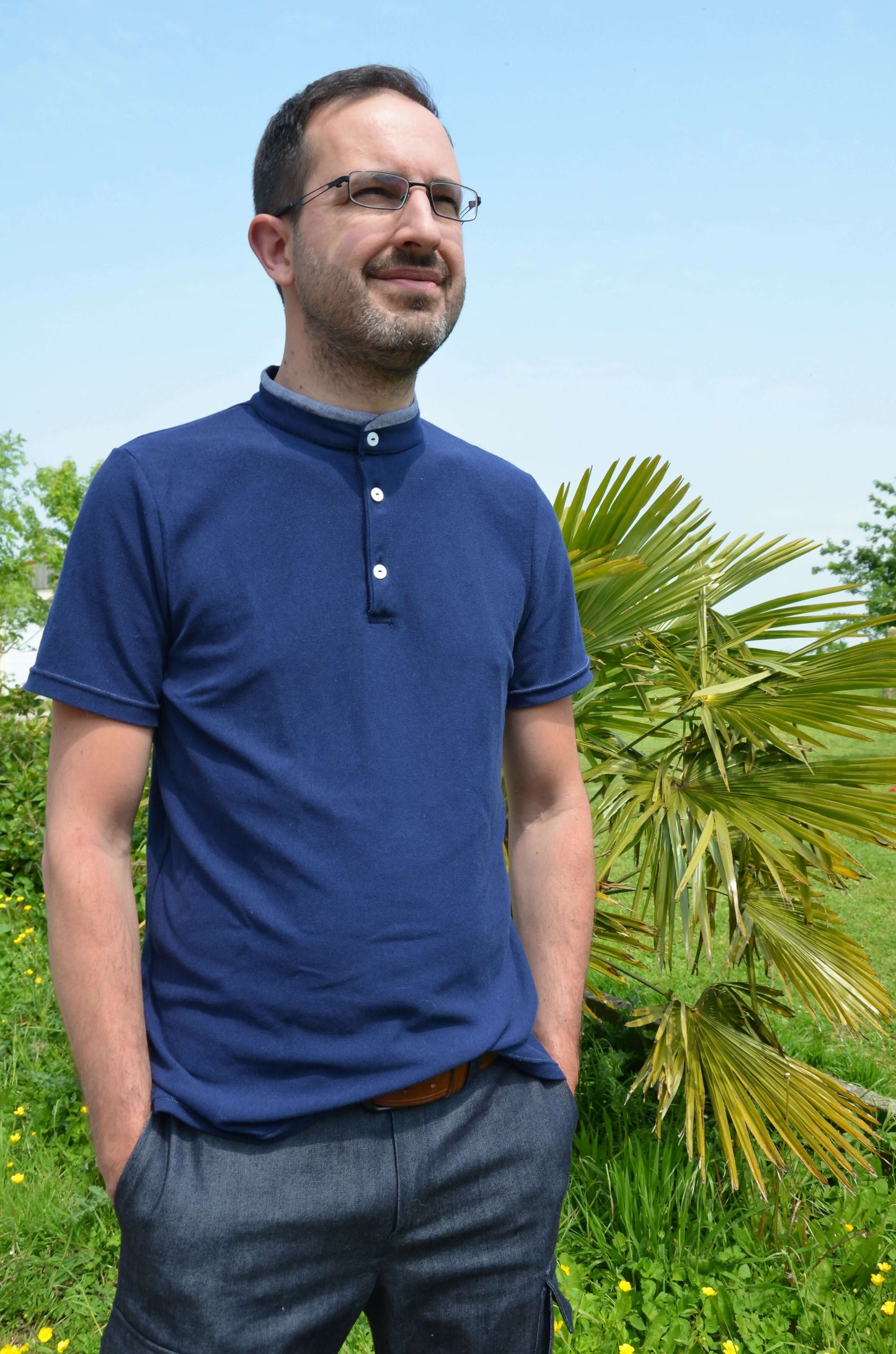 Homme portant un Polo LOPO bleu avec col officier, patron de couture PDF à télécharger, manches courtes, nature en arrière-plan.