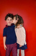 Enfants en Polo MARCOLOPO devant un mur rouge, modèle de patron de couture pdf à télécharger, mode enfant élégante et polyvalente.