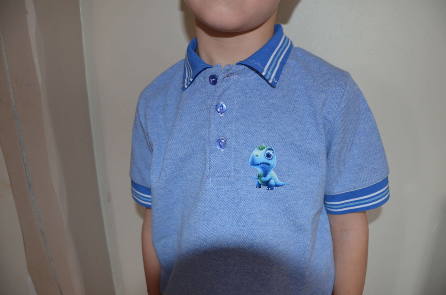 Enfant portant un Polo MARCOLOPO bleu avec modèle dinosaure, patron de couture pdf à télécharger, manches courtes rayées.