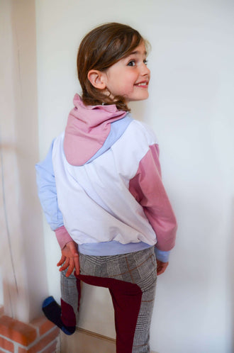 Fillette souriante portant le Pull ANGEL avec col capuche, détaillé dans le patron de couture pdf à télécharger.