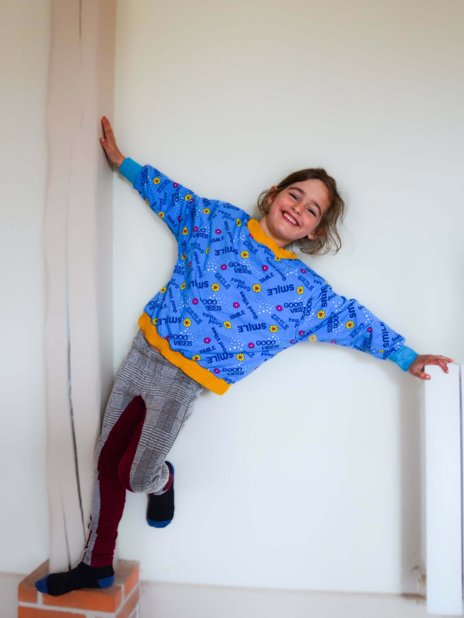 Enfant souriant portant un Pull ANGEL bleu avec motif coloré, style décontracté, patron de couture pdf à télécharger.