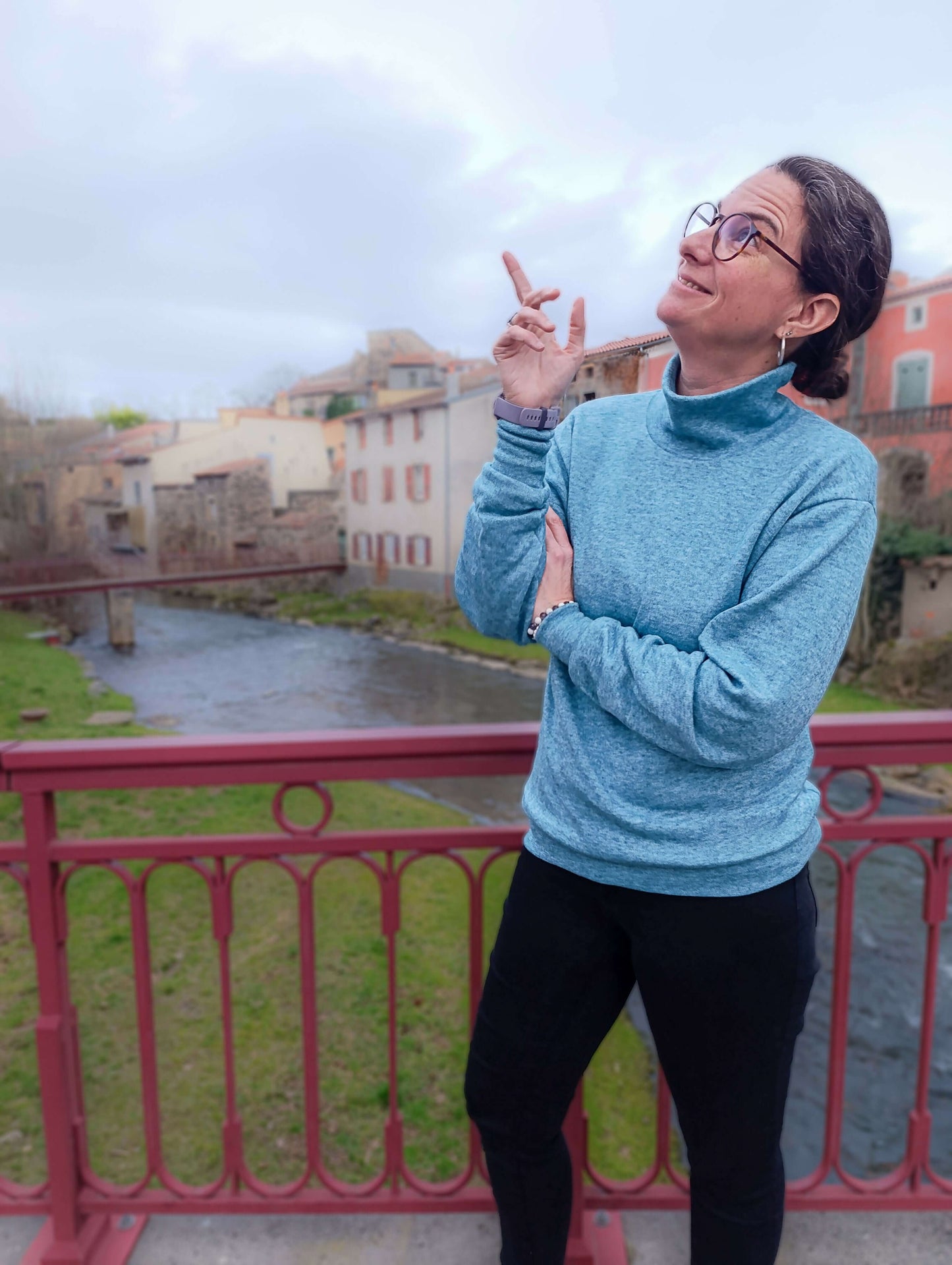 Femme portant le Pull CRYSTAL avec col roulé, manches chauve-souris, près d'une rivière en arrière-plan. Patron de couture pdf à télécharger.