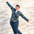 Pull sweat croisé, 34 au 56, 4 statures – Cannelle, patron de couture pdf à télécharger. Femme portant le pull devant un mur en briques.