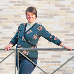 Femme portant le Pull sweat croisé, 34 au 56, 4 statures – Cannelle. Patron de couture pdf à télécharger. Fond de mur en briques.