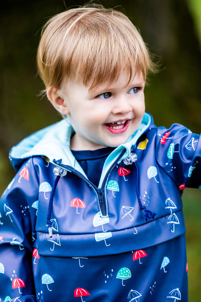 Enfant portant QUETSCHE - Le coupe-vent à poche ventrale, patron de couture pdf à télécharger, avec imprimé parapluies colorés.