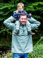 Homme portant enfant avec QUETSCHE - Le coupe-vent à poche ventrale, patron de couture pdf à télécharger, idéal pour toute la famille.
