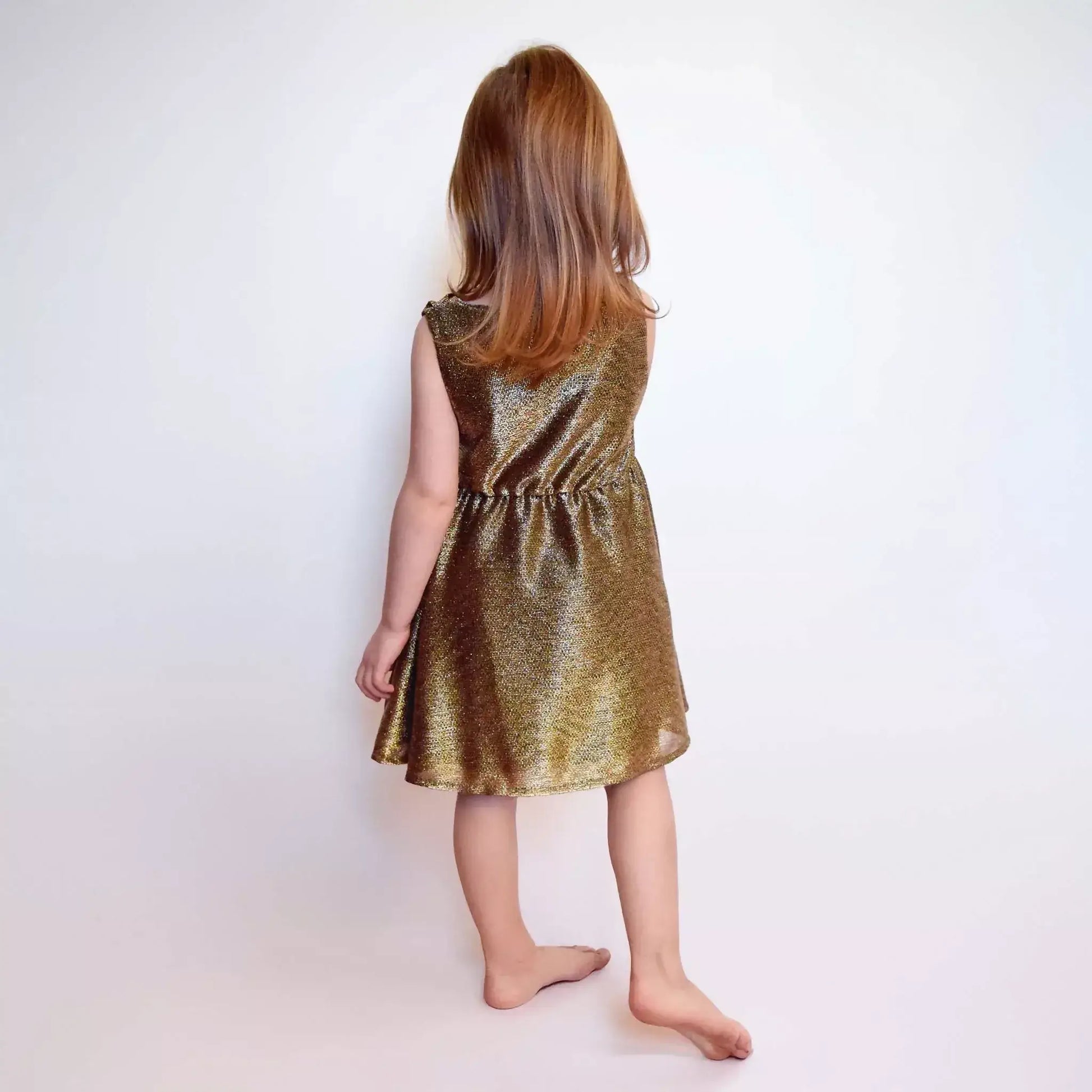 Fille portant la Robe Cylia Enfants dorée, idéale pour les 2 à 12 ans, facile à enfiler et à coudre.
