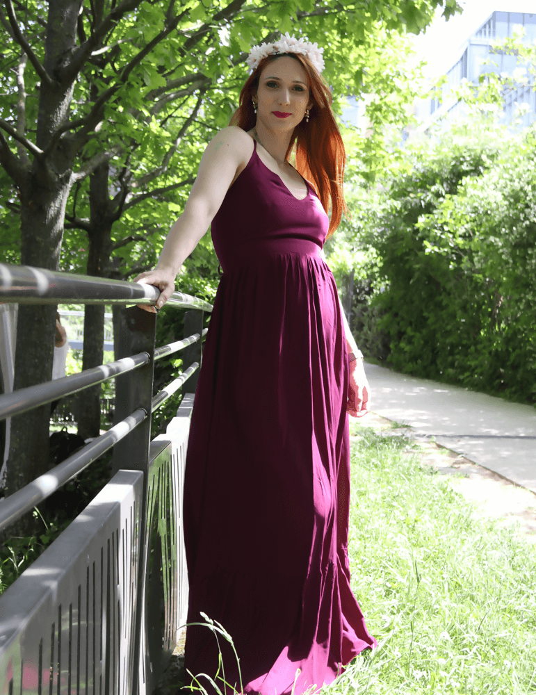 Femme en robe Delhi bordeaux dans un parc, exprimant élégance et style personnel au printemps.