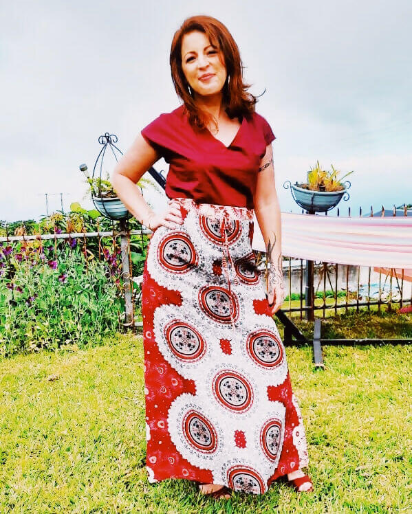 Femme portant une Robe Dysis - T 36 à 50 avec motifs colorés, dans un jardin. Patron de couture PDF à télécharger.