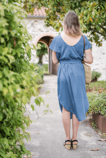 Robe FLORISSE en bleu, coupe ample, décolleté dans le dos, portée avec un sac en osier.