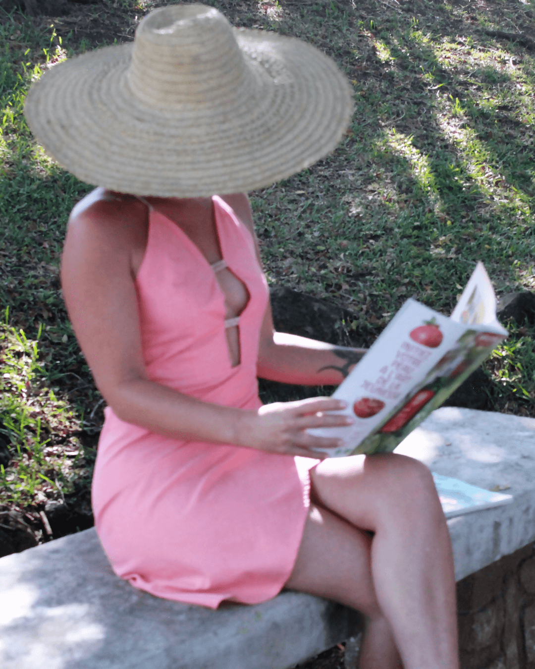 Femme portant une Robe Hécate - T36 à 50, décolleté plongeant, lisant dehors sous un chapeau, patron de couture pdf à télécharger.