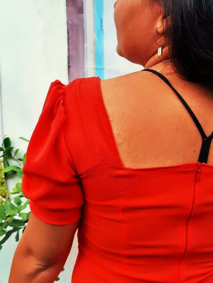 Vue arrière d'une robe rouge à manches ballons, mettant en évidence le décolleté et les détails de la coupe.