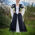 Robe Princesse Margaux Femmes portée dans un jardin, souligne sa silhouette médiévale avec jupe ample et manches ballon.