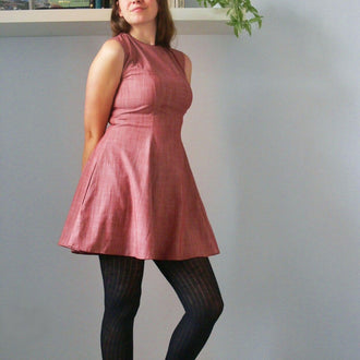 Femme portant la Robe Rochelle - 32 au 56 avec passepoil, patron de couture pdf à télécharger, style rétro et poches sur les côtés.