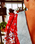 Détail d'une robe avec manches froncées et décolleté dans le dos, dans un décor de plantes d'intérieur.