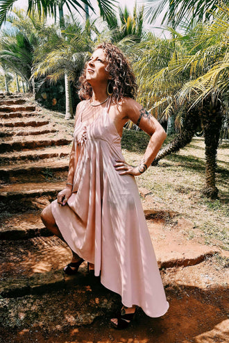 Femme portant la Robe Thoé - T36 à 50, patron de couture pdf à télécharger, coupe asymétrique, ensoleillée dans un jardin tropical.