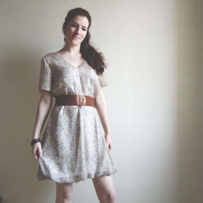 Femme portant la Robe "Topalyne" du 32 au 60, patron de couture PDF à télécharger, avec une ceinture et manches bouffantes.