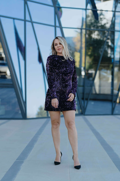 Robe - XS-XL - ARTISTA en velours violet, design moderne, modèle femme posant devant des reflets de verre.