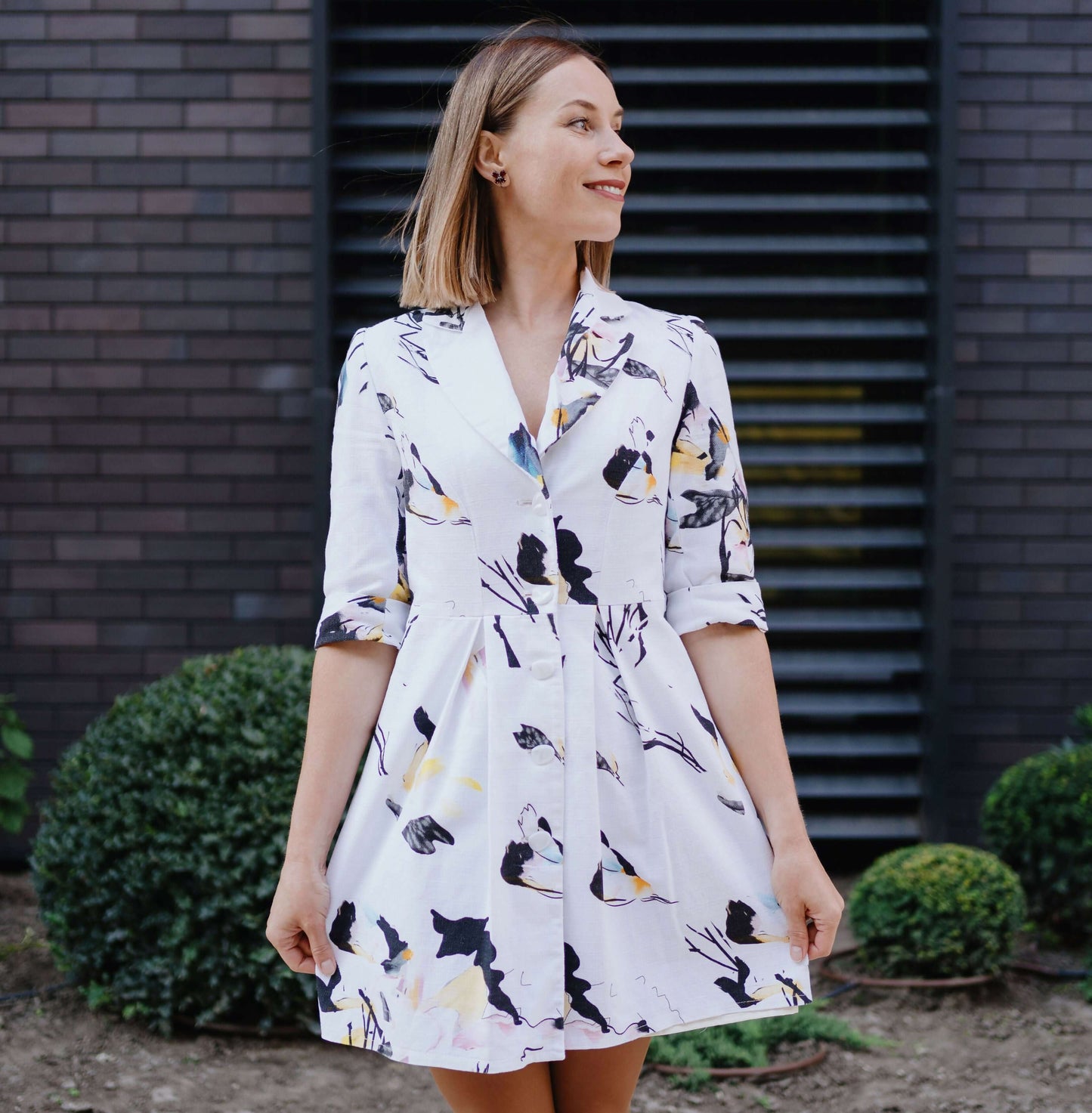 Robe XS-XL - SOULMATE, patron de couture PDF à télécharger, femme portant une robe imprimée florale devant un mur de briques.